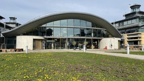 The Centre for Mathematical Sciences in spring, with flowers blooming on the grass outside