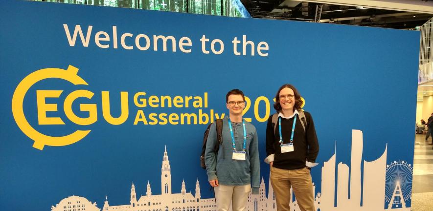 Dominic Orchard and Jack Atkinson in front of EGU General Assembly Sign